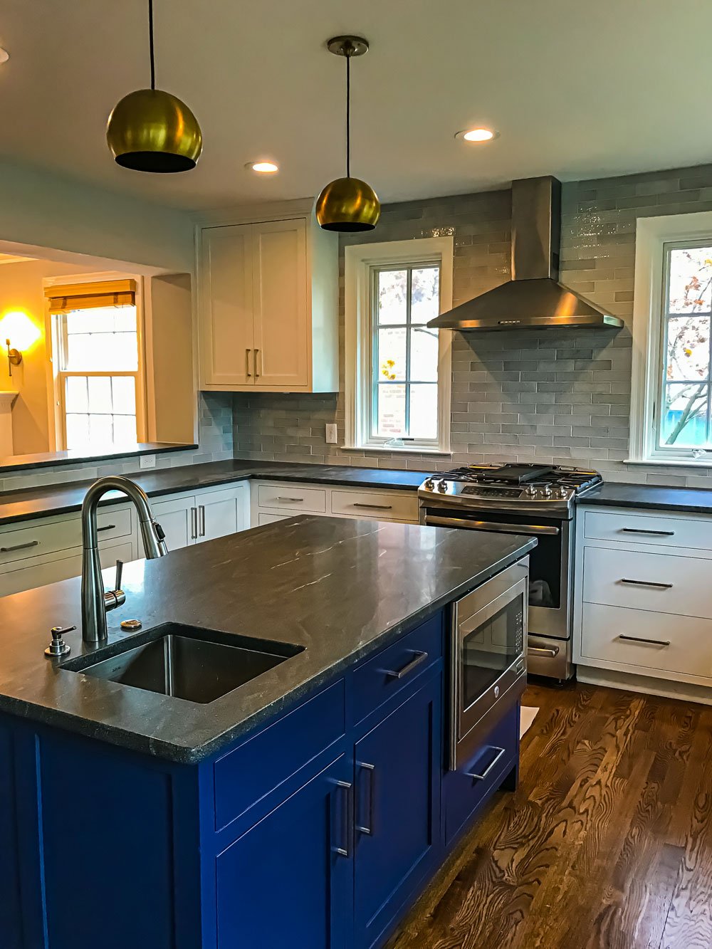 Modern kitchen island with dark grey granite counter and grey stone backsplash