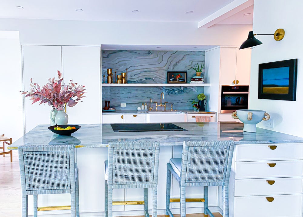 Kitchen island with three blue wicker seats, and a large electric stove built into the counter