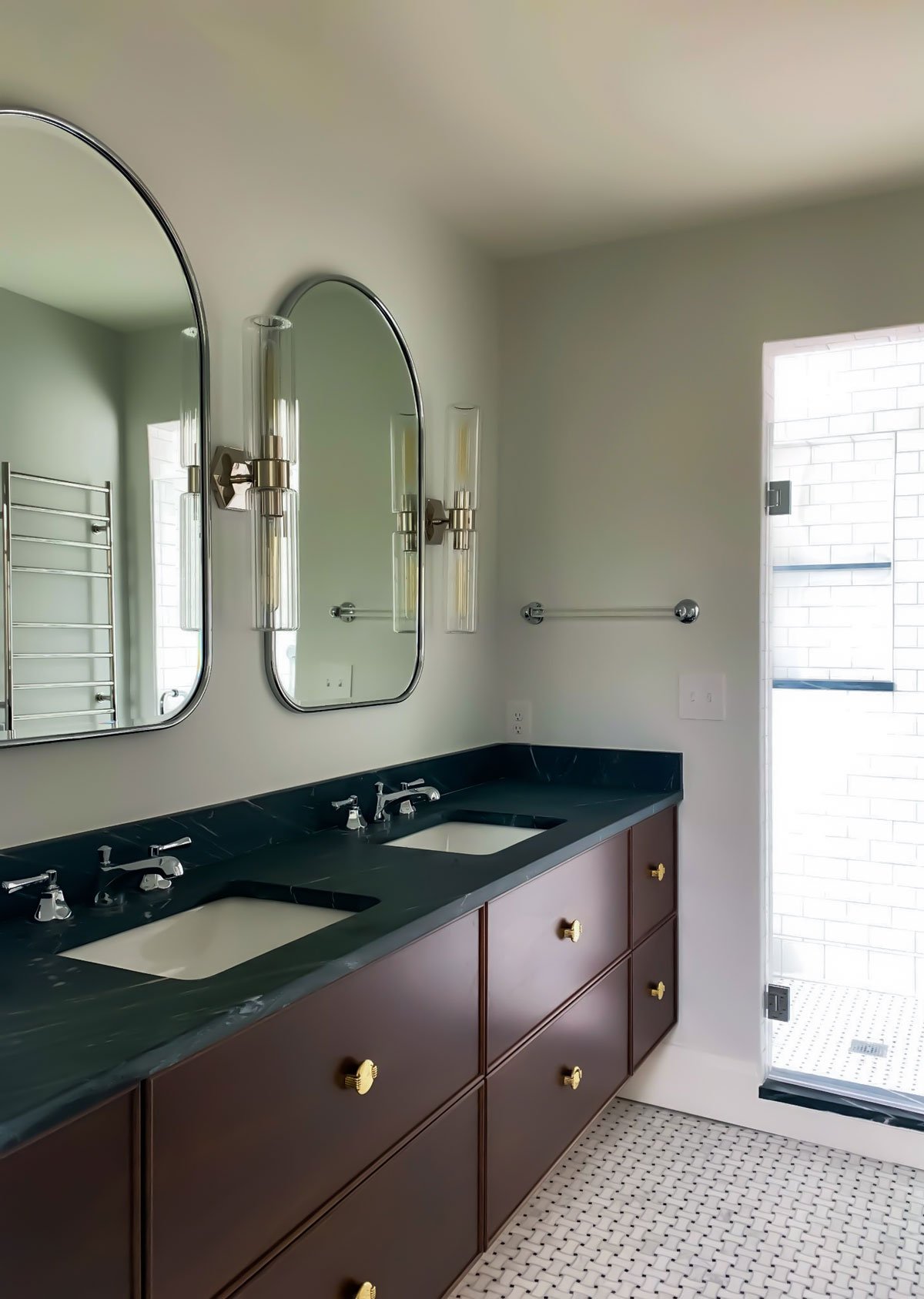 Bathroom with green countertop, double vanity mirrors, and a walk-in shower with sliding glass door