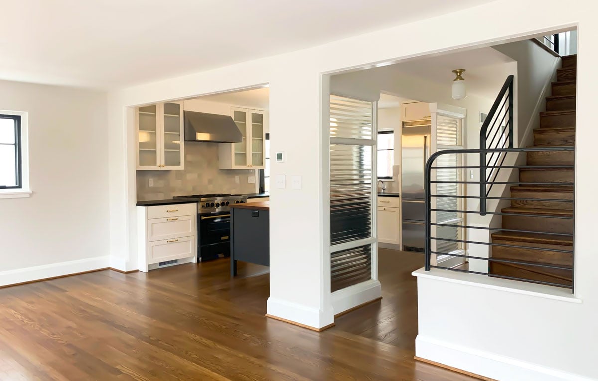Modern stairway with metal railing leading into kitchen and open living room and dining room