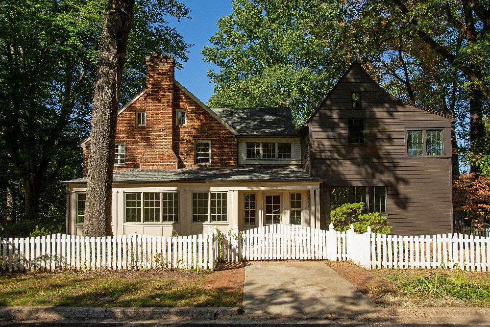 Two story home with a large sidewalk out front and a white picket fence surrounding the front yard