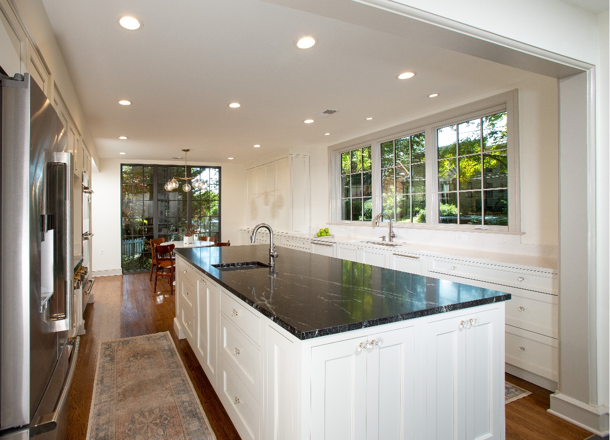 Home kitchen with dark wood ebony flooring, and a black granite countertop with can lighting fixtures