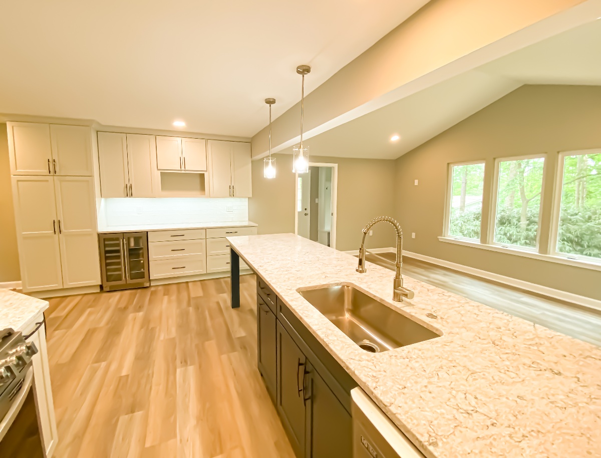 Kitchen island with cream colored granite countertop and accenting white cabinets and drawers
