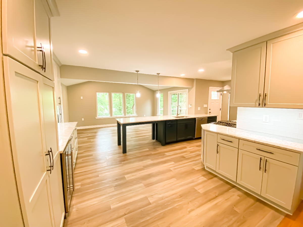 Light colored birch wood flooring inside a remodeled kitchen with both black and white accents and floor to ceiling kitchen storage
