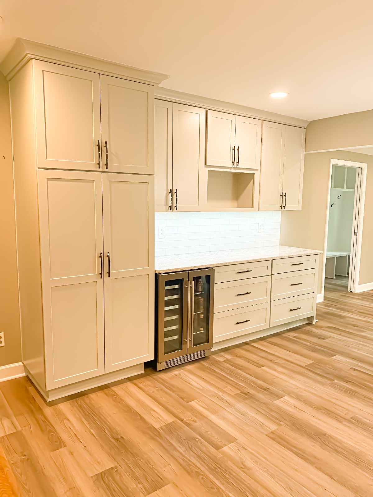 White kitchen cabinets with small steel refrigerator or wine chiller built in