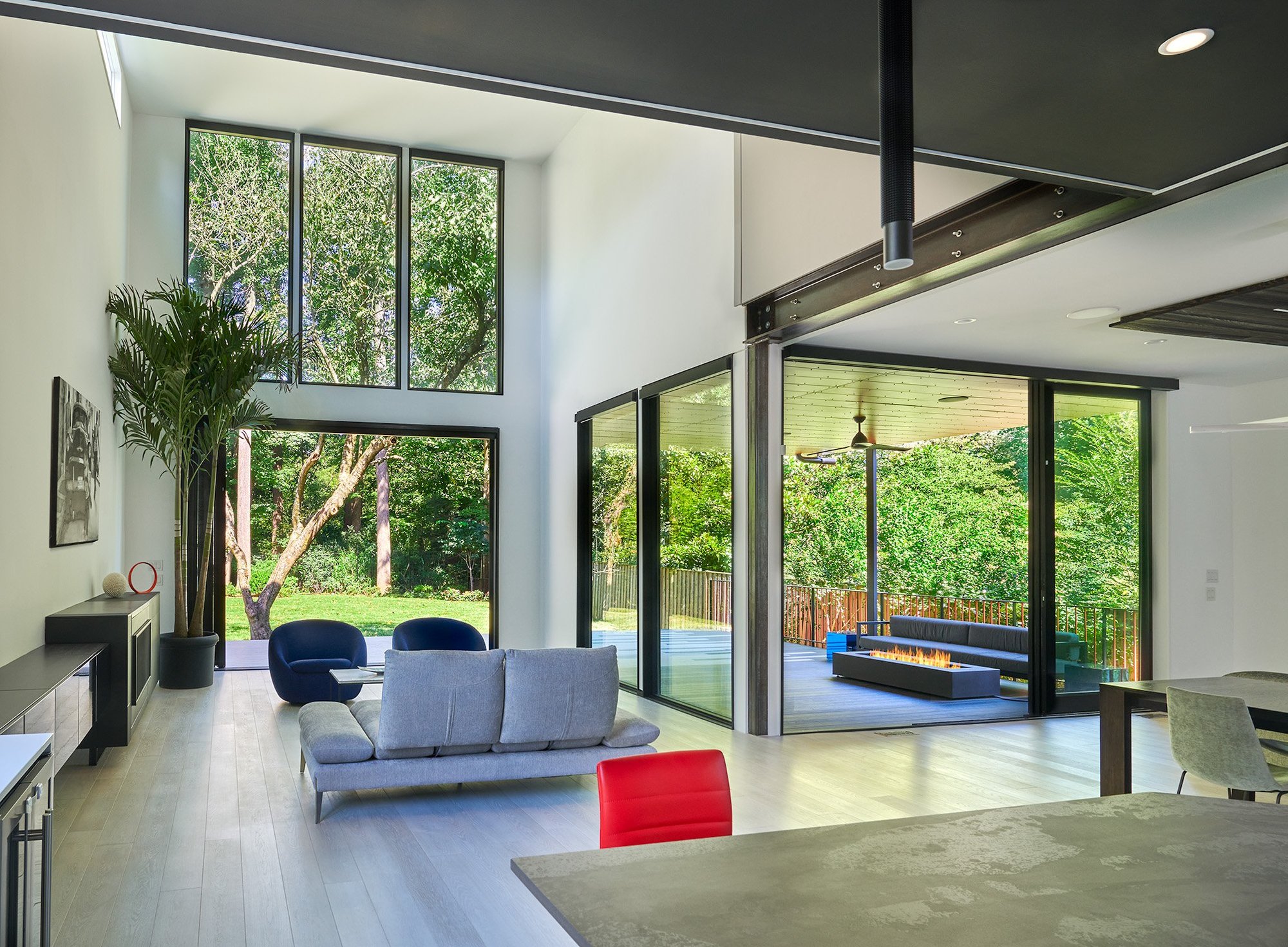 Looking out the back of a modern home that has expansive windows, large open doors and a deck.