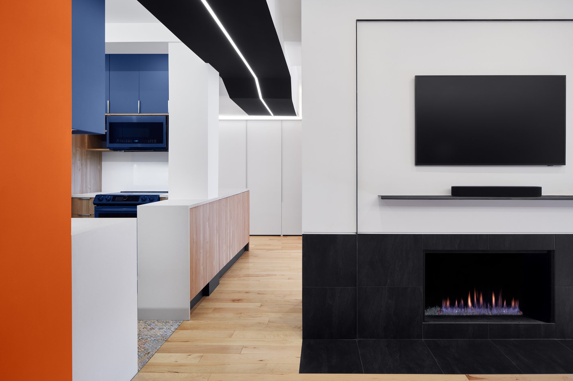 A living room with a fireplace transitioning into the kitchen.  A decorative ceiling design stands out.