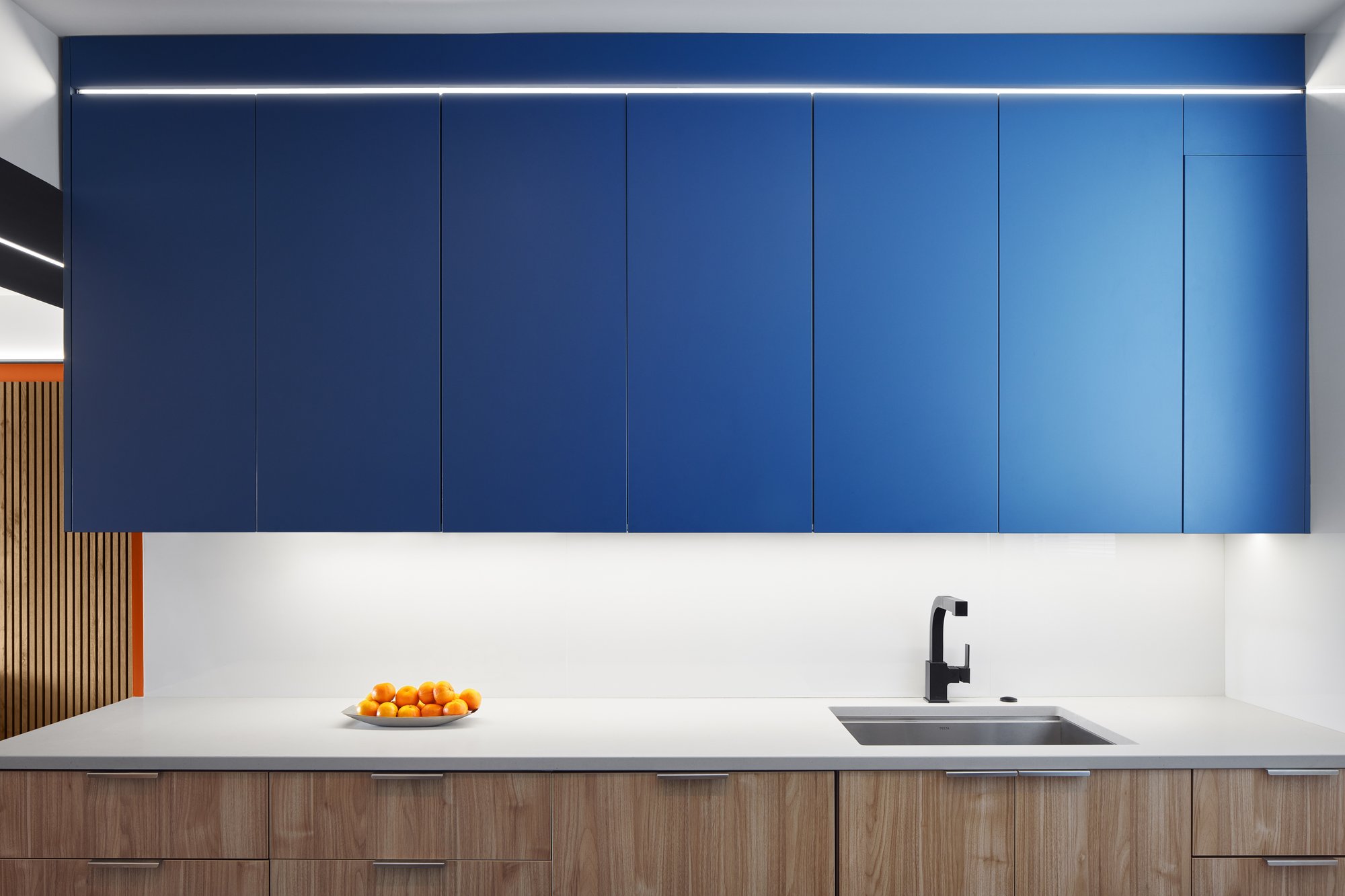 Kitchen with white countertops and stunning blue cabinets.  A bowl of oranges sits on the counter.