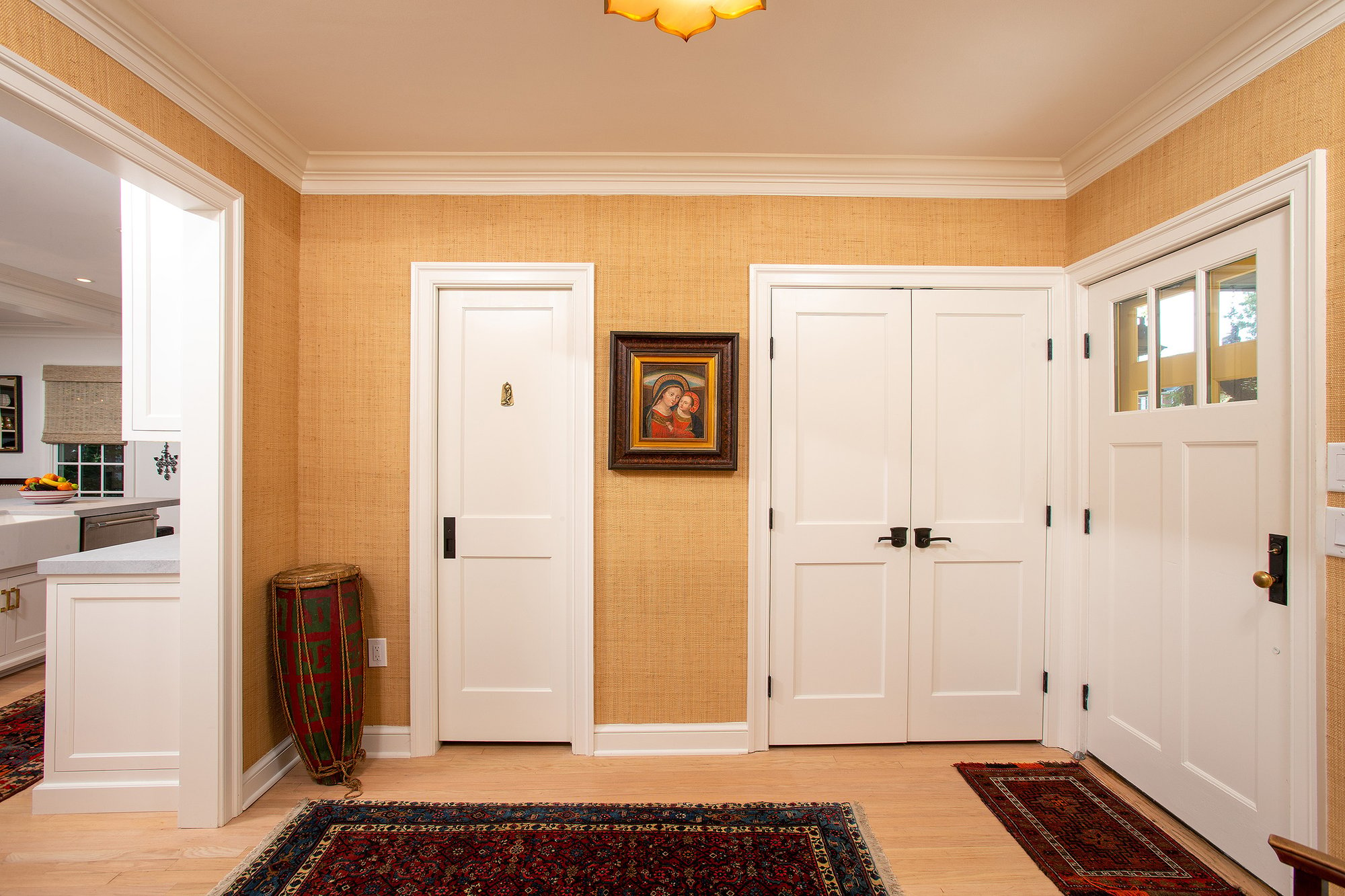 Front entrance and mudroom of a home with a coat closet and additional linen closet and yellow textured wallpaper