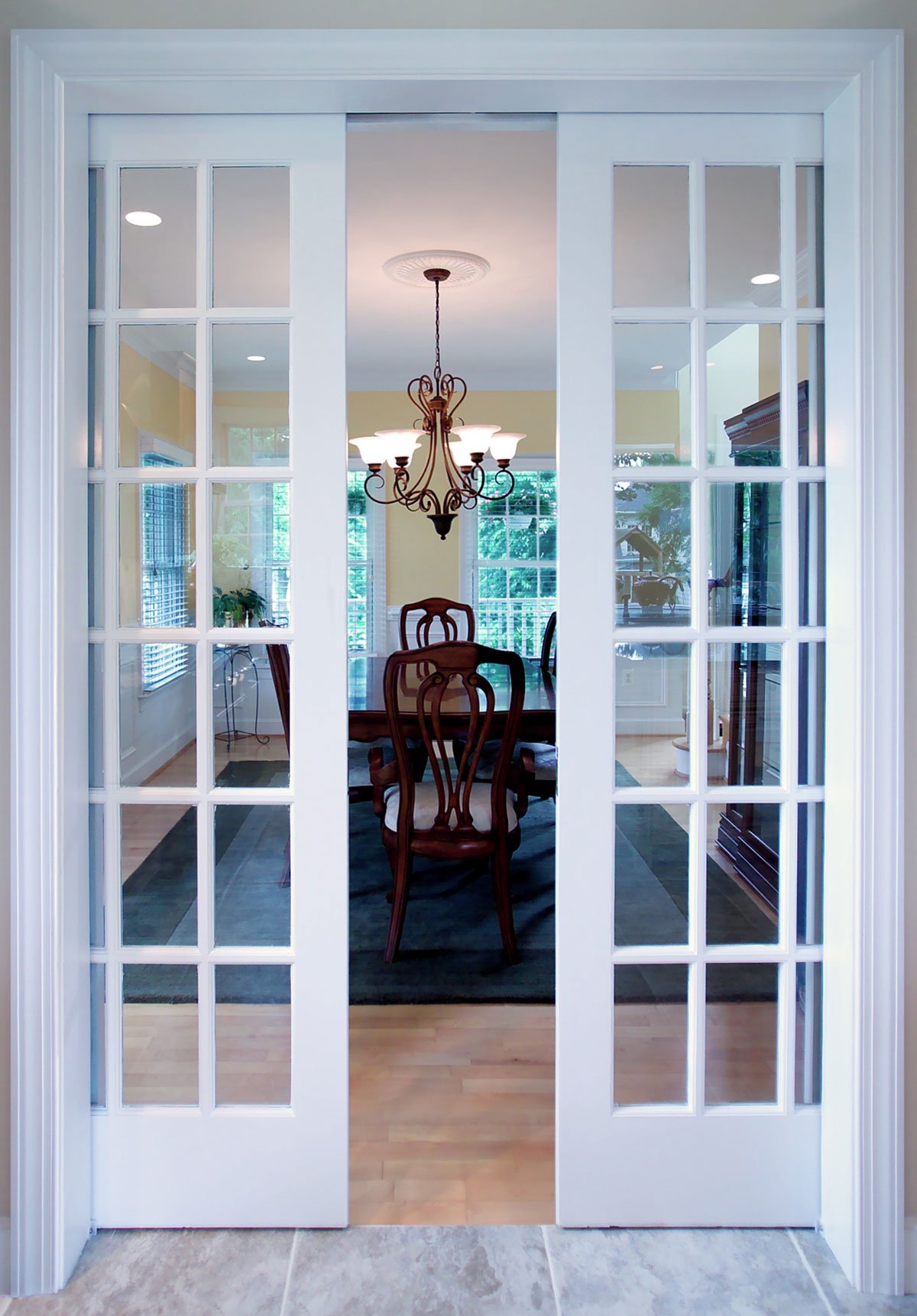 Sliding white wooden double doors lead into a family dining room with seating for four