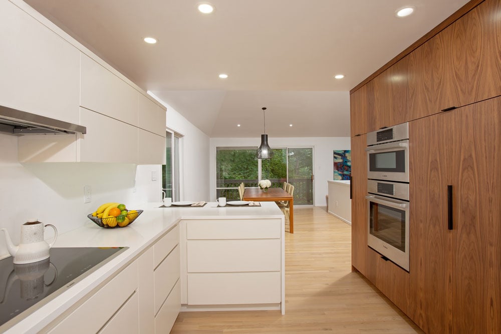 Kitchen that overlooks a family dining room with white wood and traditional wooden cabinets