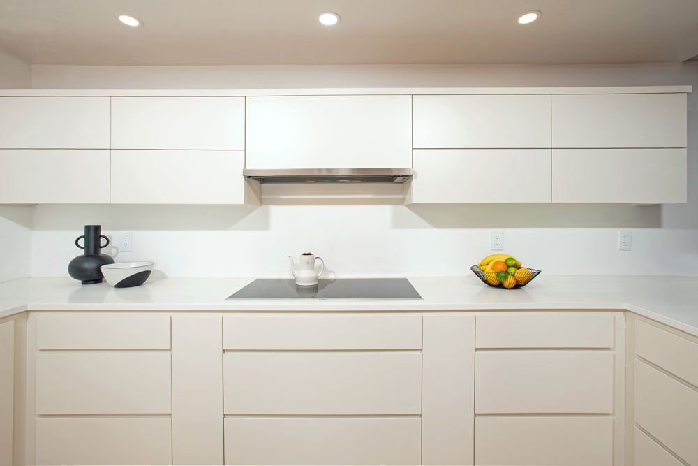 White soft-close cabinets with invisible handles and three LED can lights above the kitchen counter