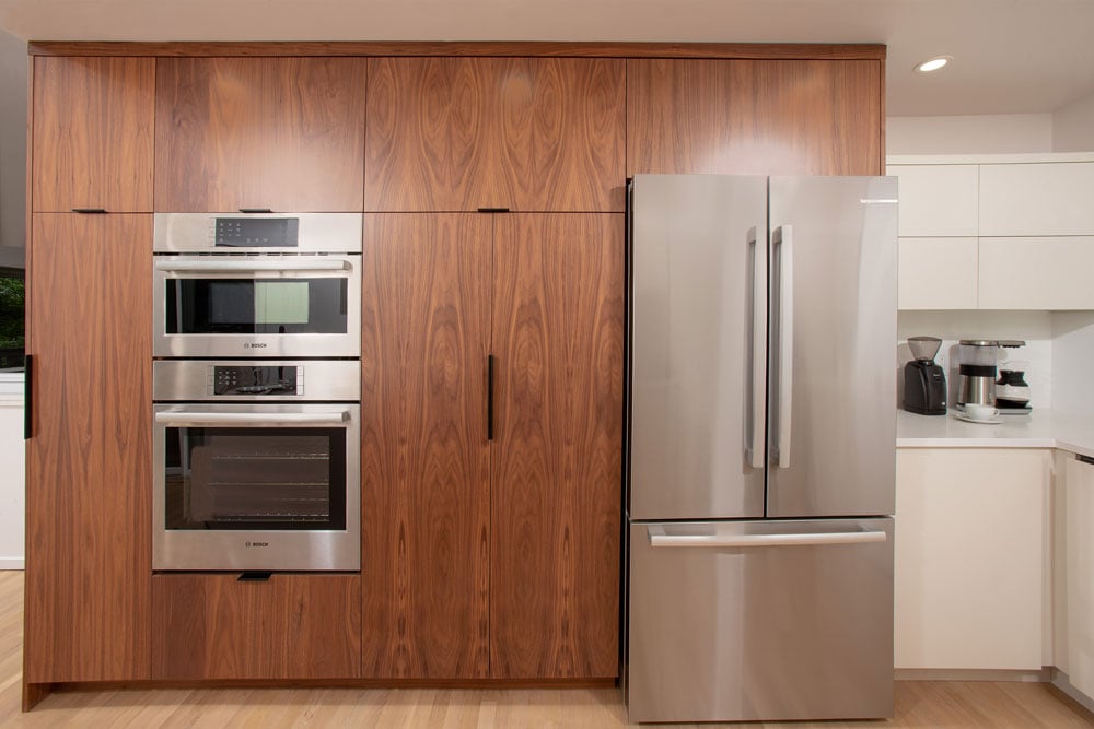 Wooden storage cabinets with steel fridge and built-in oven combo next to cabinetry