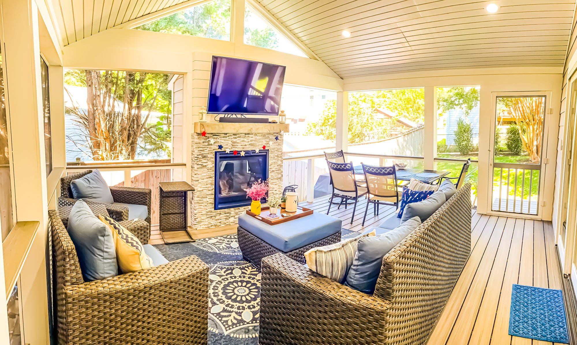 Screened in deck with couches and a television over a fire place.