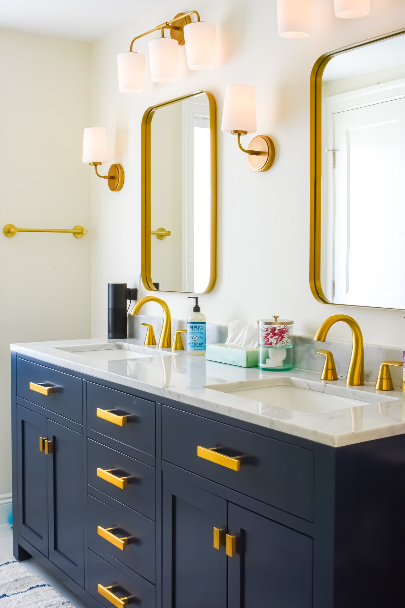 A dual sink blue bathroom vanity with gold rimmed mirrors. 