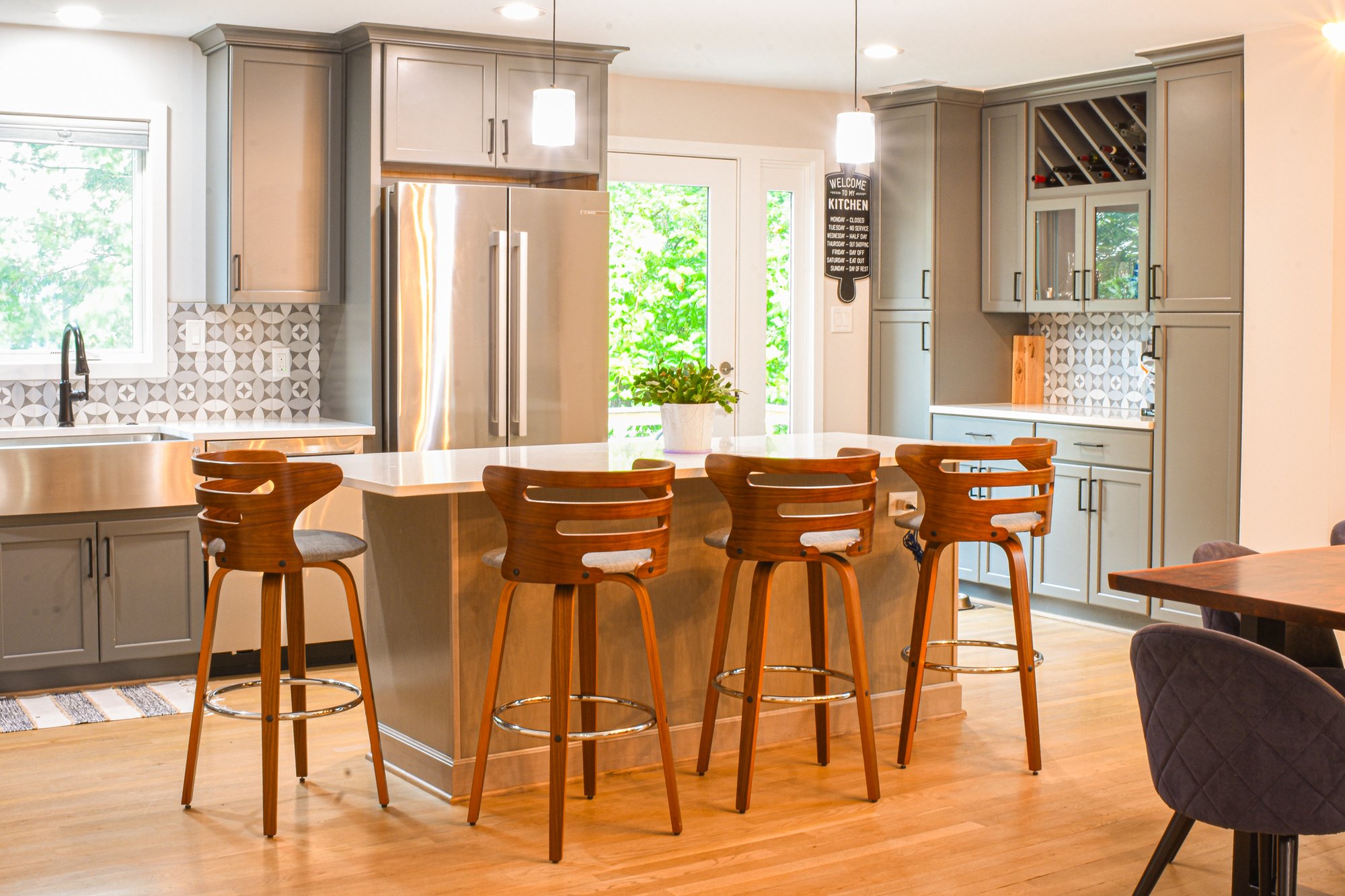 Well lit kitchen island with four wooden bar stool chairs for serving and entertaining