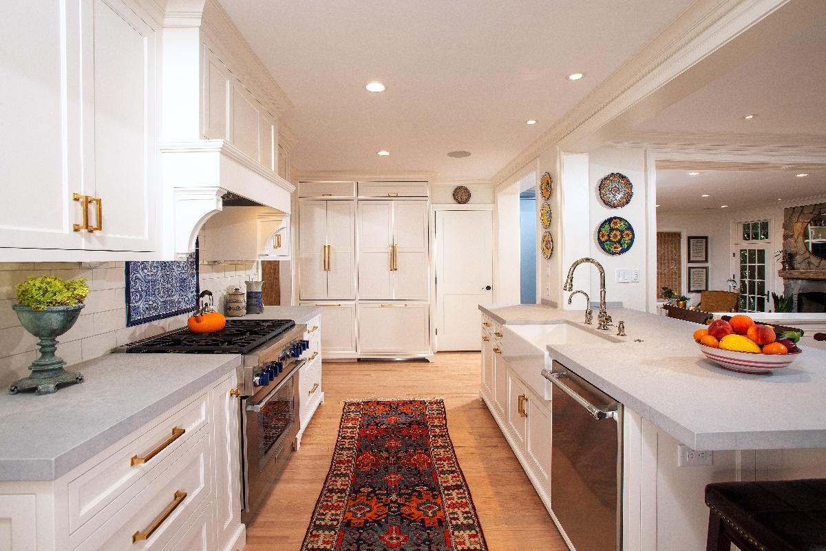 kitchen walkway with a blue and red runner rug between  the kitchen oven and dishwasher